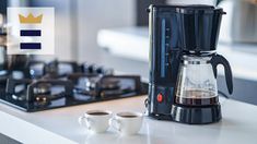 a coffee maker and two cups on a kitchen counter