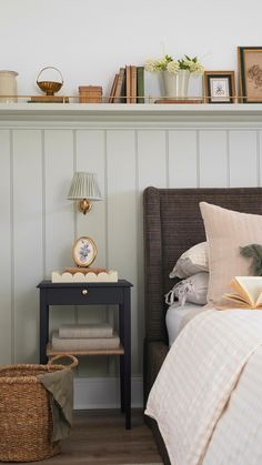 a bed room with a neatly made bed next to a night stand and a book shelf