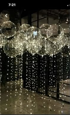 some lights hanging from the ceiling in front of a mirror with balls on it and stars all over them