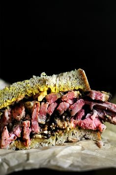 a corned beef sandwich is cut in half and sitting on a piece of parchment paper