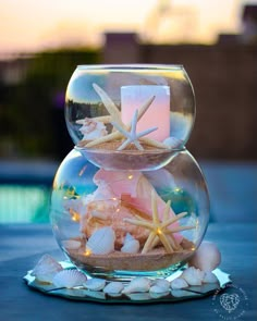 two fishbowes filled with sand and starfish on top of a blue table