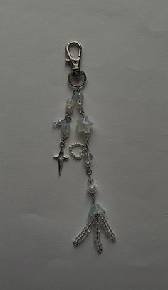 a key chain with charms attached to it on a white surface, in the shape of an arrow