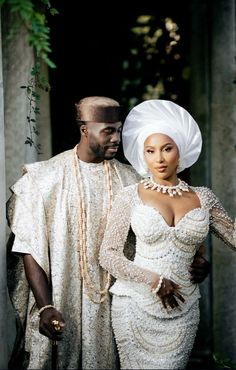 a man and woman dressed in white standing next to each other wearing head coverings