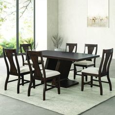 a dining room table and chairs in front of a large window with an area rug on the floor