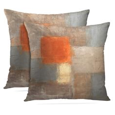 two pillows sitting next to each other on top of a white surface with orange and grey squares