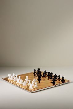 a chess board with black and white pieces on it in front of a gray background