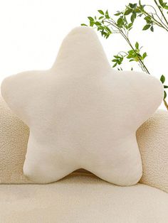 a white star pillow sitting on top of a couch next to a potted plant