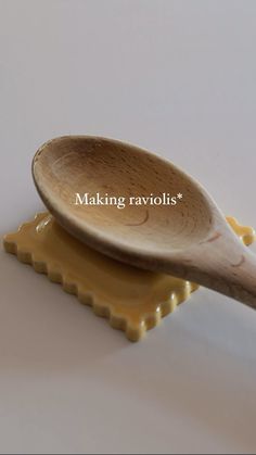 a wooden spoon sitting on top of two yellow plates with words making ravioli's