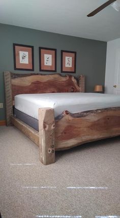 a bed made out of wood in a room with carpeting and pictures on the wall