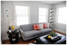 a living room filled with furniture and windows covered in white shuttered shades on either side of the couch