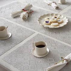 a table topped with two cups of coffee and plates filled with pastries on top of it