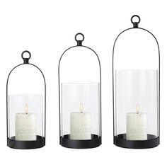 three glass lanterns with candles inside them