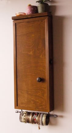 a wooden cabinet mounted to the side of a wall with two mugs on it