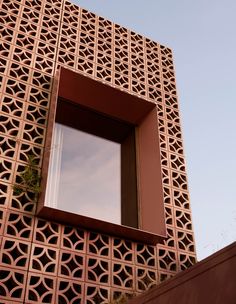 a window on the side of a building with an intricate pattern and brown trim around it