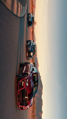 three sports cars driving on a road near the ocean