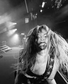 a woman with her hair blowing in the wind on stage at a rock and roll concert