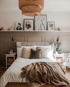 a bed with pillows, blankets and pictures on the wall