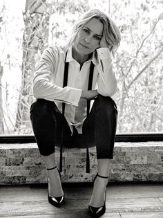 a black and white photo of a woman sitting on a ledge with her legs crossed