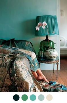 a woman's feet are sitting on a bed in front of a blue wall