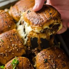 someone is picking up some sliders from the casserole dish with cheese and herbs