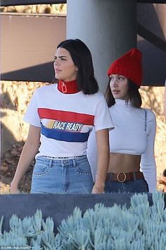 two women in matching outfits walking down the street with one wearing a red, white and blue t - shirt