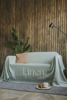 a living room with a couch covered in a blanket and coffee cup on the floor