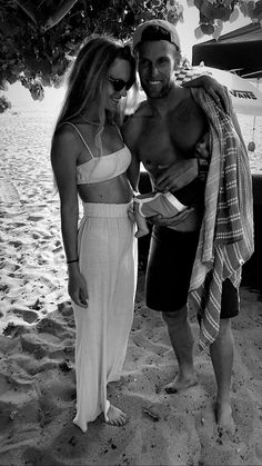 a man standing next to a woman on top of a beach