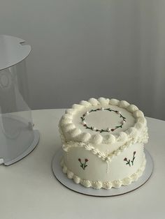 a white cake sitting on top of a table next to a clear plastic container filled with frosting