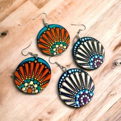 three colorful earrings are sitting on a wooden surface