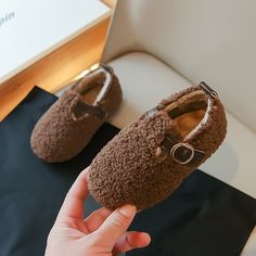 someone is holding up their brown baby shoes