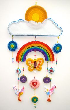 a colorful wind chime hanging from the side of a wall with a rainbow and clouds on it