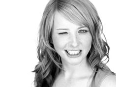 a black and white photo of a woman with long hair smiling at the camera while wearing a tank top