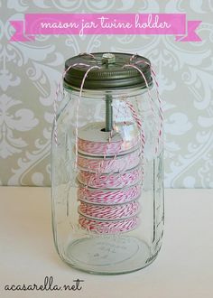 a mason jar filled with pink and white twine spools on top of a table