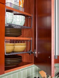 an open cabinet in a kitchen with dishes on the shelves and plates stacked inside it