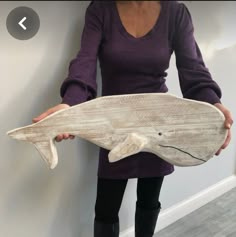 a woman holding a wooden fish sculpture in her hands