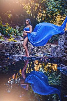 a woman in a blue dress is standing on the water with her arms around her body