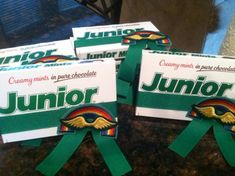 three unopened boxes of junior chocolates with green ribbons around them on a counter