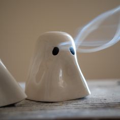 two white ghost figurines sitting on top of a wooden table