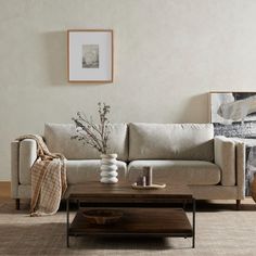 a living room with a couch, coffee table and pictures on the wall behind it