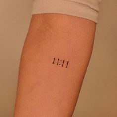 a person with a small tattoo on their arm that says 11 11 in black ink