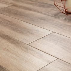 a white vase sitting on top of a wooden floor next to a brown tile floor