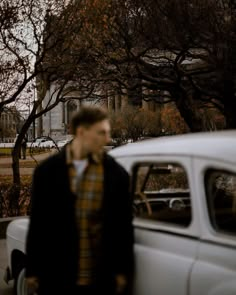 a man standing next to an old white car