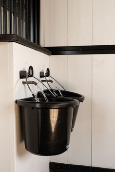 a black bucket hanging from the side of a wall with utensils in it