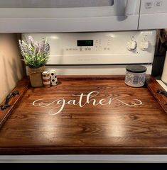 a wooden cutting board with the word gather written on it