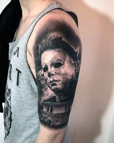 a man's arm with a tattoo of a house and a scary face on it