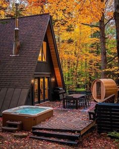 an outdoor hot tub next to a cabin in the woods with autumn leaves on the ground