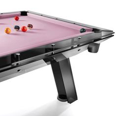 a pink pool table with black legs and red balls on the top, in front of a white background