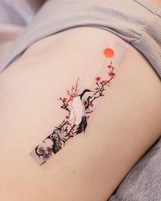 a woman's thigh with a tattoo on the side of her stomach and an image of a bird perched on a tree branch