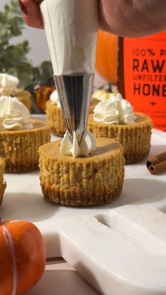 a person is spreading icing on small desserts with pumpkins in the background