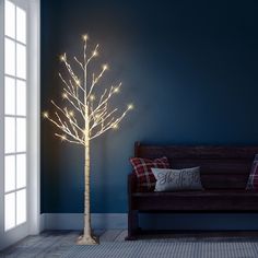 a white lighted tree next to a couch